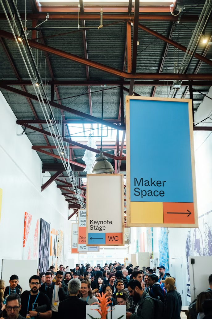 Crowded maker space event hall with hanging signage